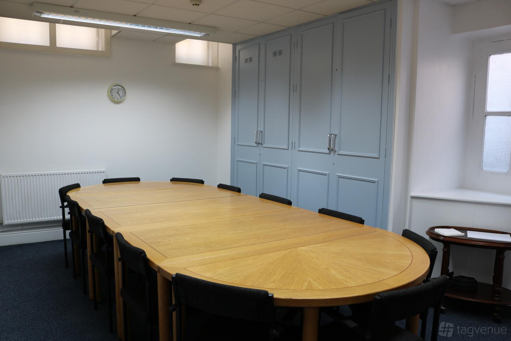 An event venue with a large oval wooden meeting table, black chairs, and built-in light blue cabinets at Space in Marylebone.