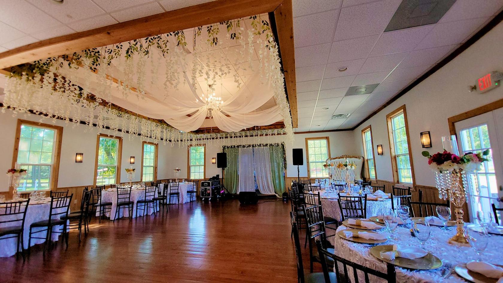 An event venue with sheer draped ceiling, hanging florals, round tables with sequin linens at JB La Hacienda.