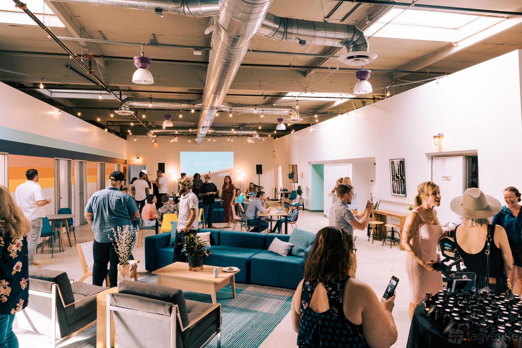 A warehouse venue with exposed ductwork, skylights, and lounge seating at Rogue Collective.