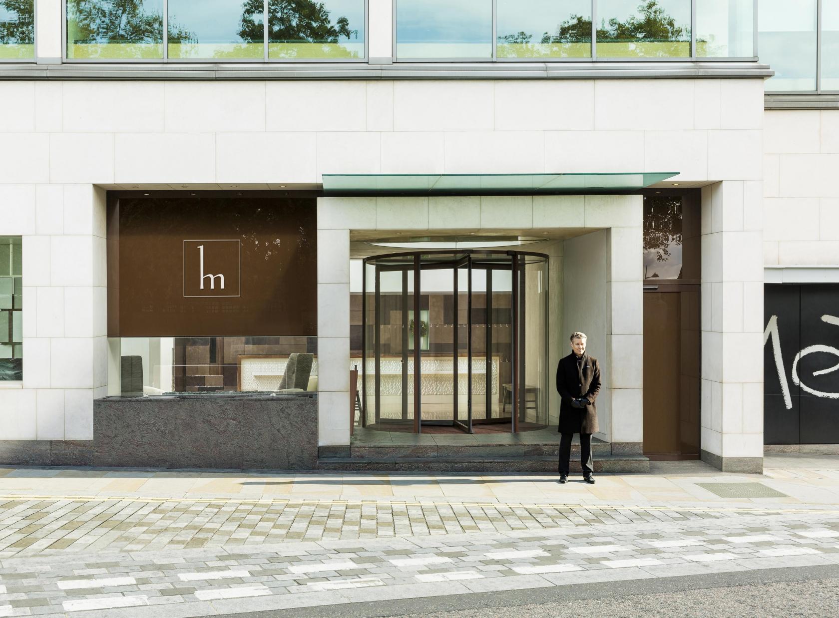 A meeting centre with a glass revolving door entrance, stone facade, and a doorman at COMO Metropolitan London.