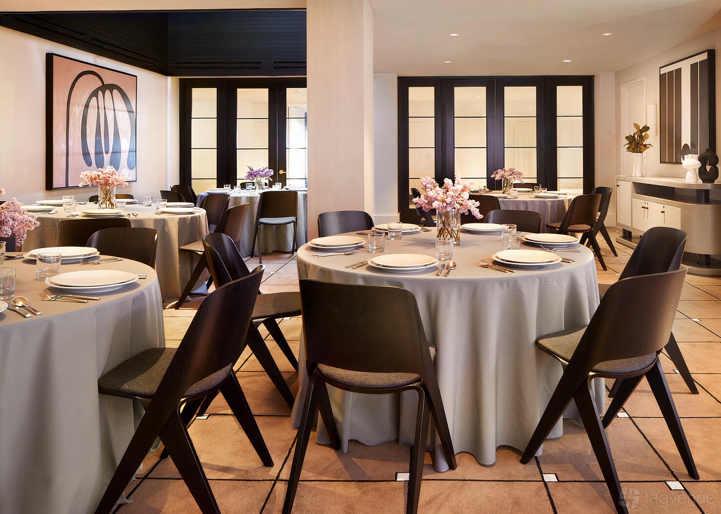 A function room with round tables draped in gray linens, set with white plates and floral centerpieces at Kimpton Alton Hotel Fisherman's Wharf.