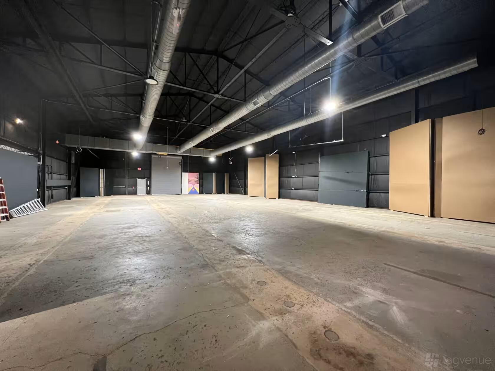 A warehouse with an open concrete floor, exposed ceiling beams, and industrial lighting at Pullman Yards.