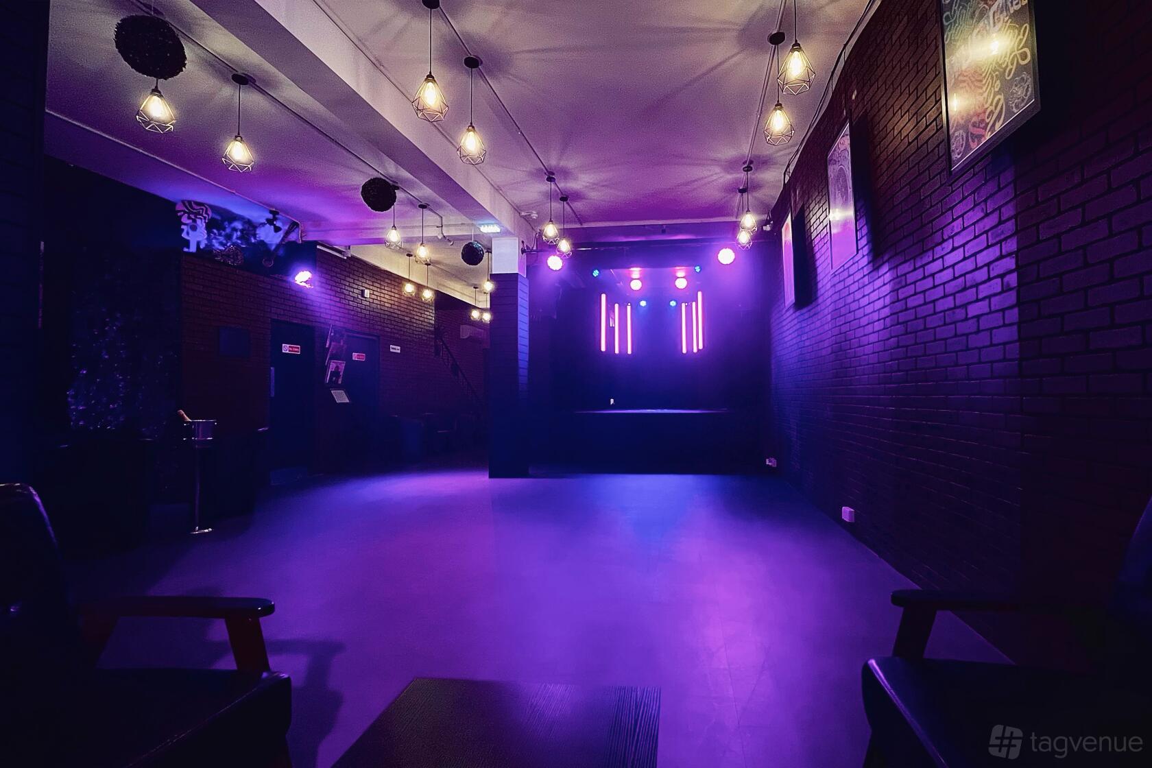 An event venue with exposed brick walls, stage lighting, and hanging pendant lights at Fusion Creative Studios.