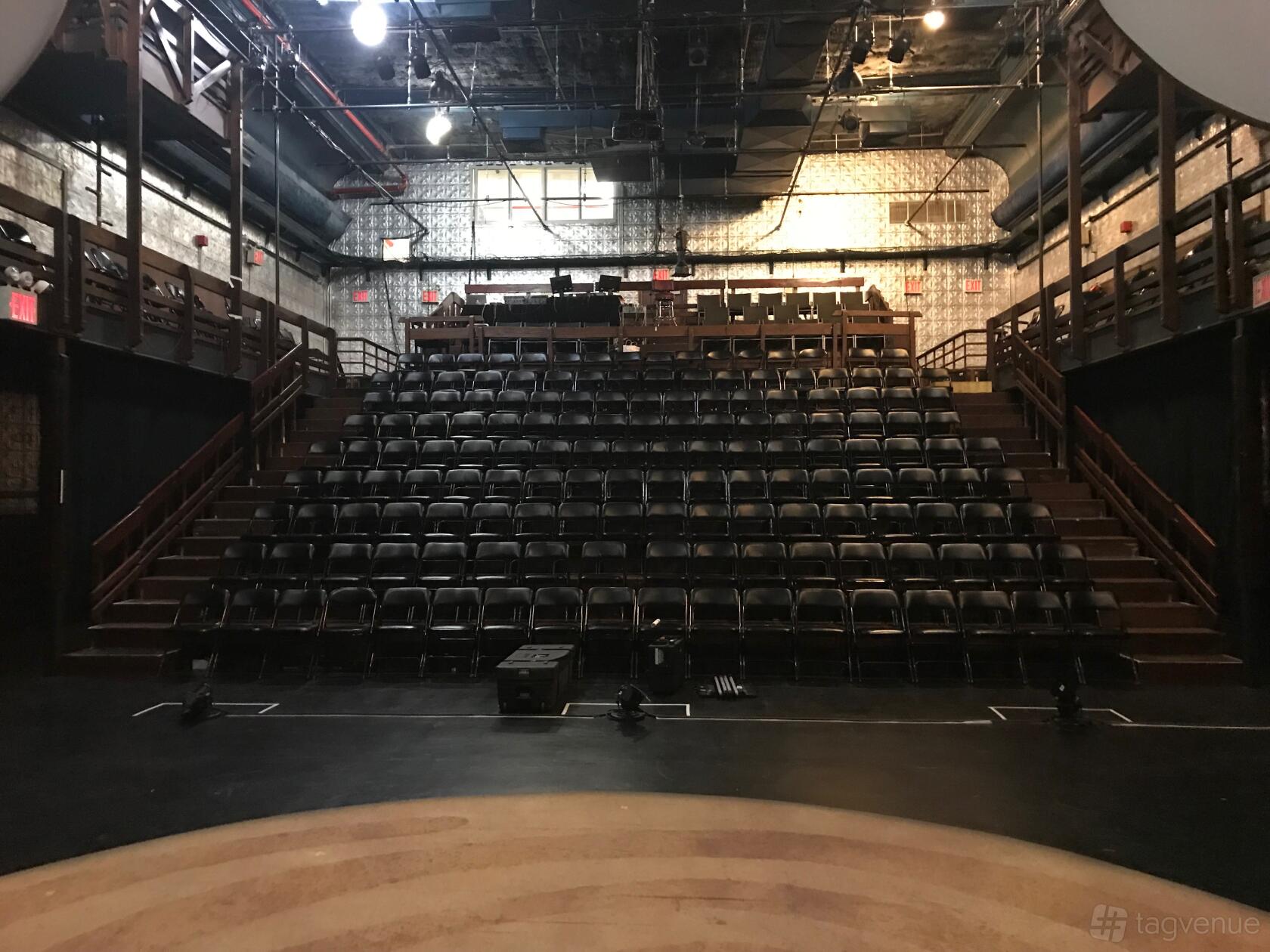 A theatre with tiered seating, metal wall panels, and wood railings at La MaMa Experimental Theatre Club.