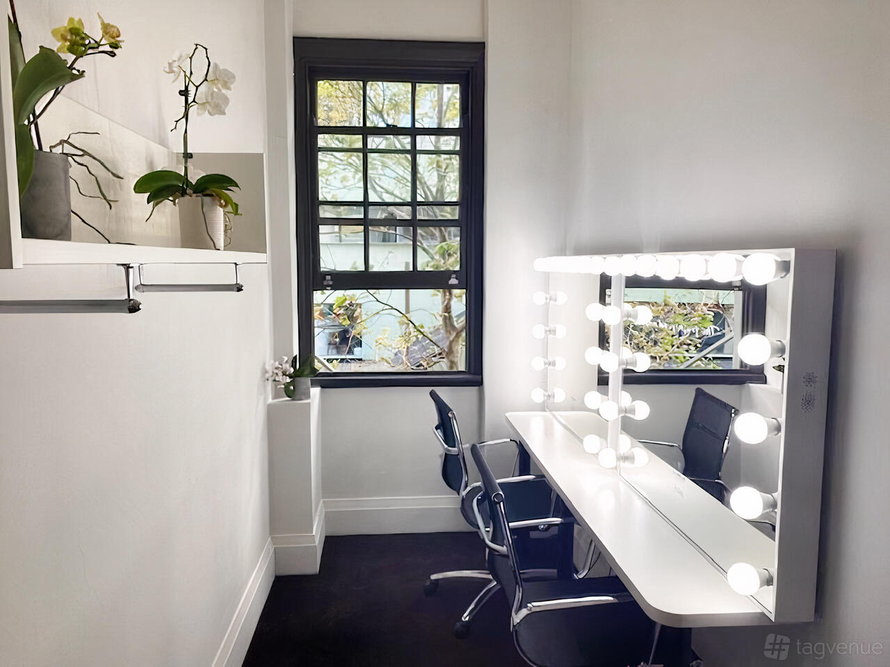 A creative space with a lighted makeup station, salon chairs, and large window at Studio 2 Potts Point.