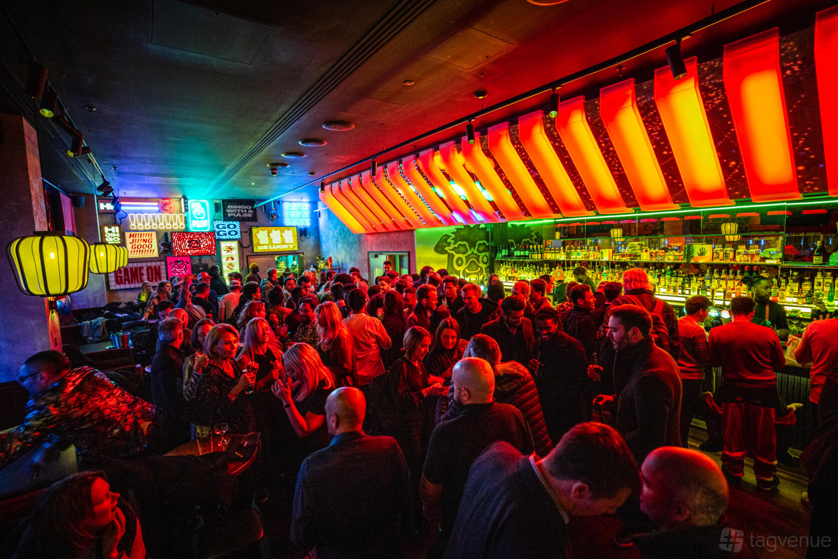 A bar with neon lighting, illuminated signage, and a crowded dance floor at Hijingo - Worship Street, London.