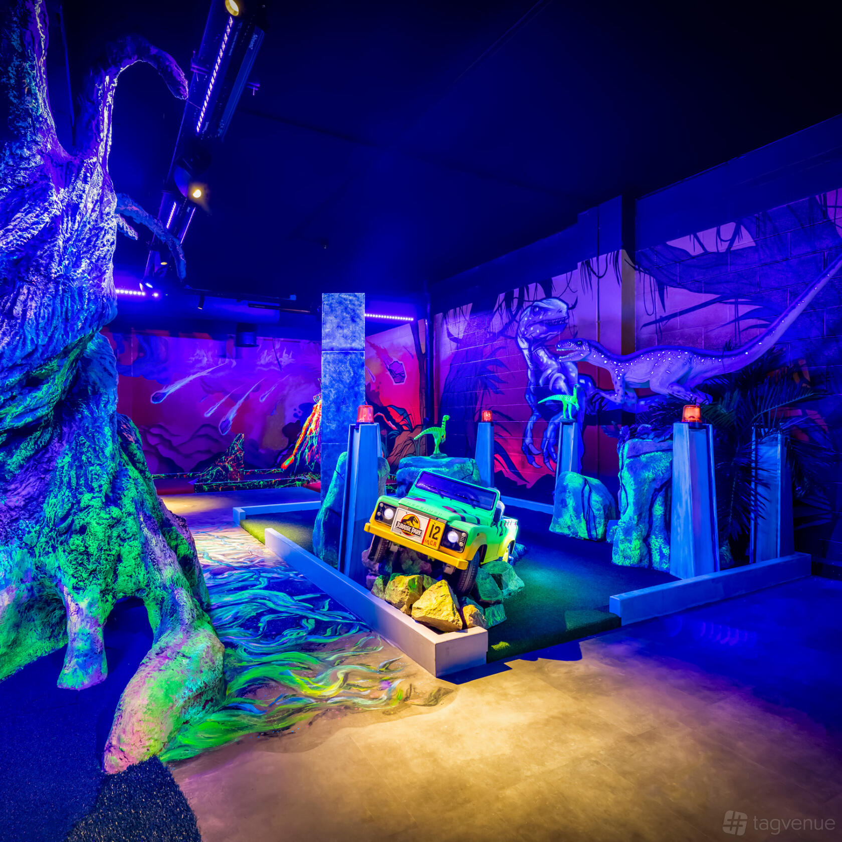 An event space with neon-lit mini golf, dinosaur murals, and a themed vehicle obstacle at The Light Redhill.