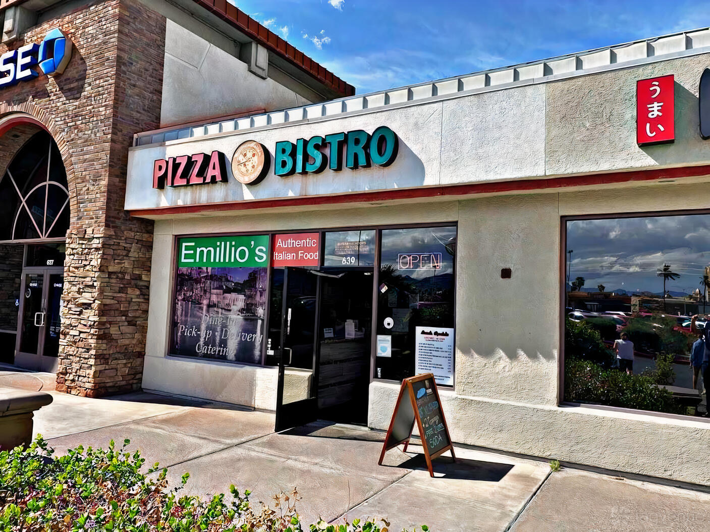 A restaurant with a storefront featuring large windows, outdoor signage, and a sidewalk menu board at Emilio’s Pizza & Bistro Inc.