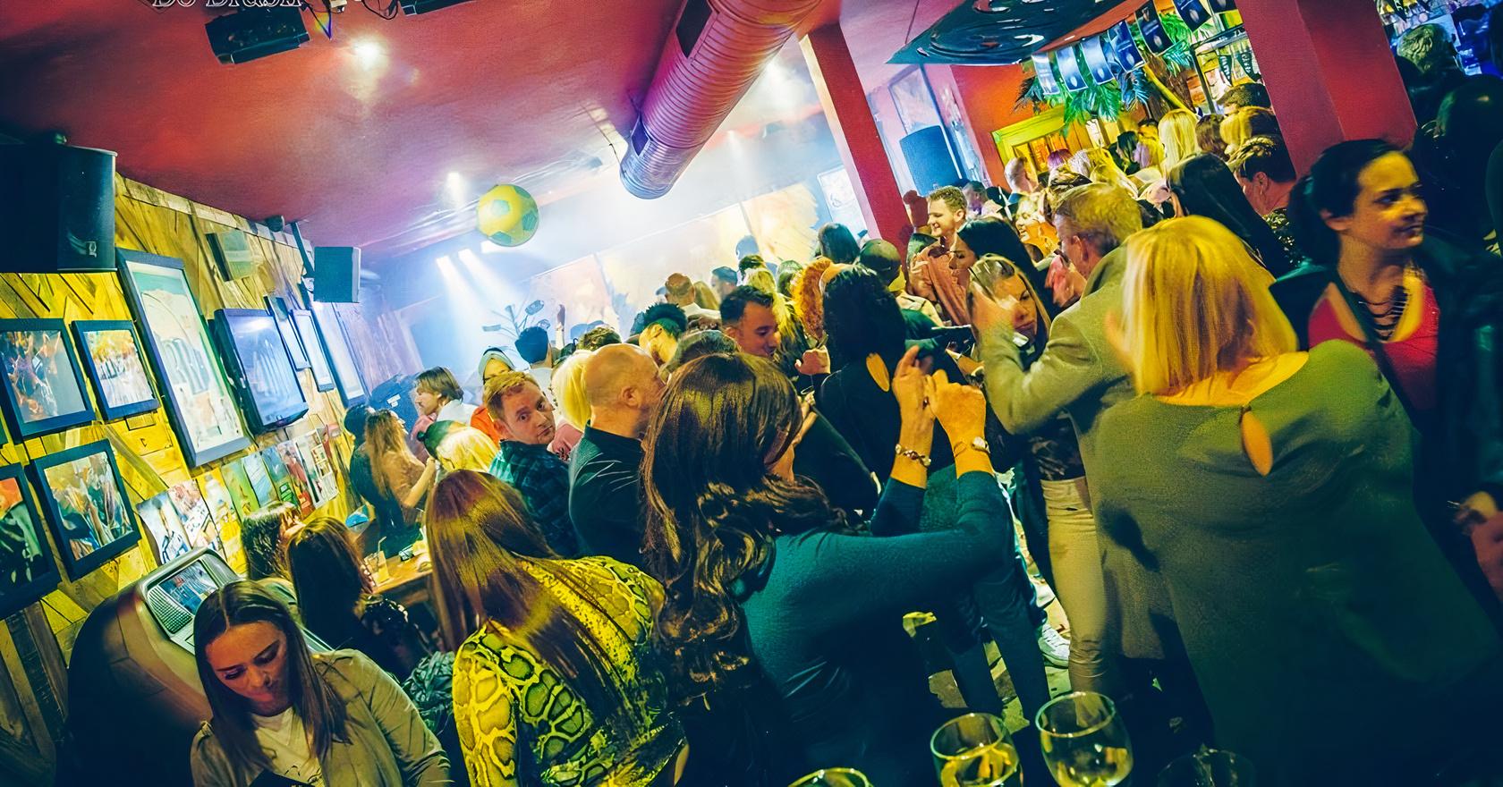 A restaurant dining room with colorful walls, lively crowd, and ambient lighting at Boteco Do Brasil Glasgow.