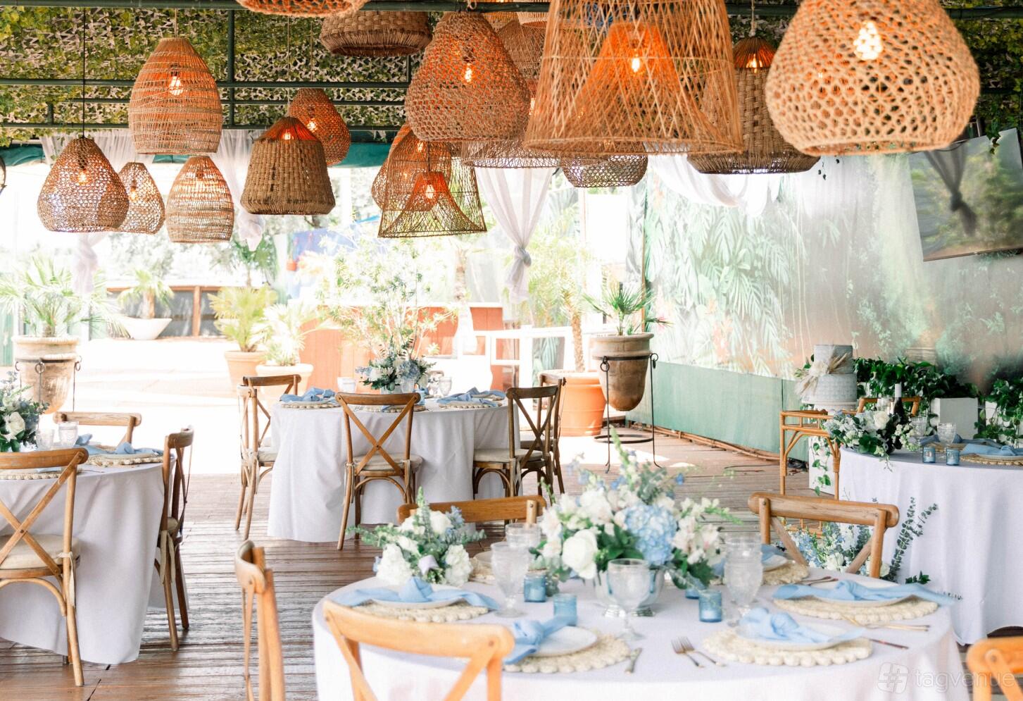 A hotel restaurant with woven pendant lights, wood chairs, and round tables with white linens at Sands Harbor Resort and Marina.