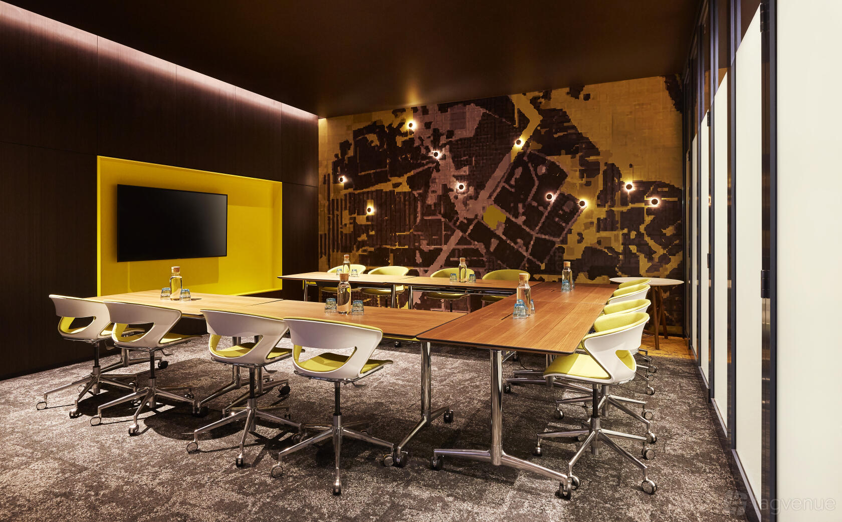 A meeting room with a U-shaped table setup, ergonomic chairs, wall-mounted TV, and abstract wall art at Holiday Inn Express Newcastle.