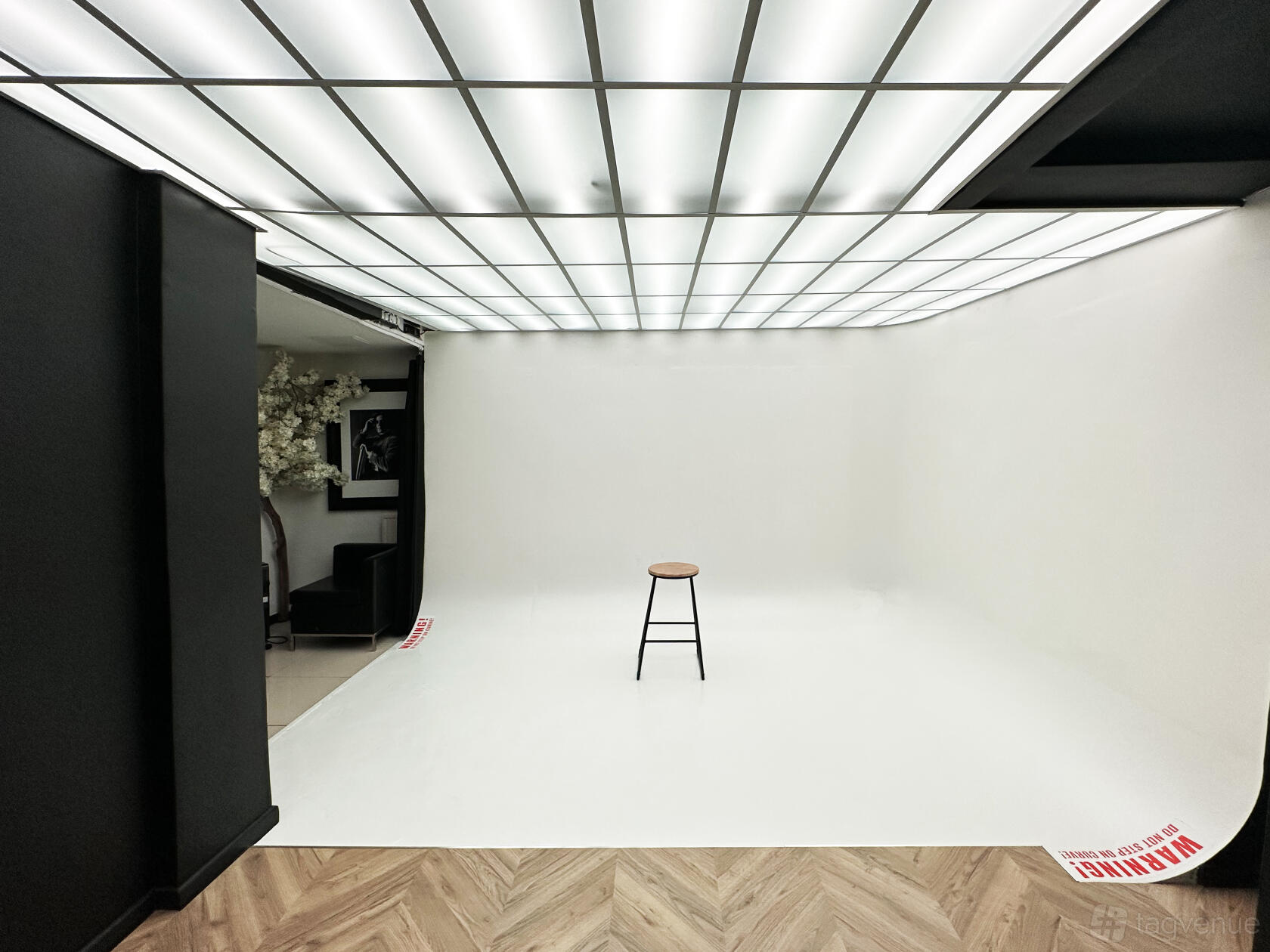 A photo studio with a seamless white cyclorama wall, blackout panels, and a single stool at EL Agency.