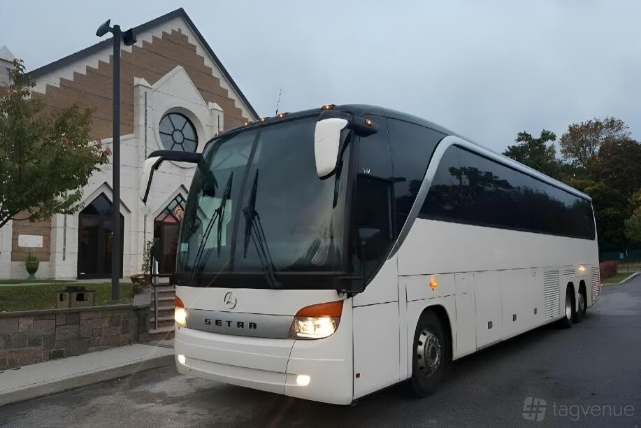 A large white party bus with tinted windows parked in front of a building at US Bargain Limo.