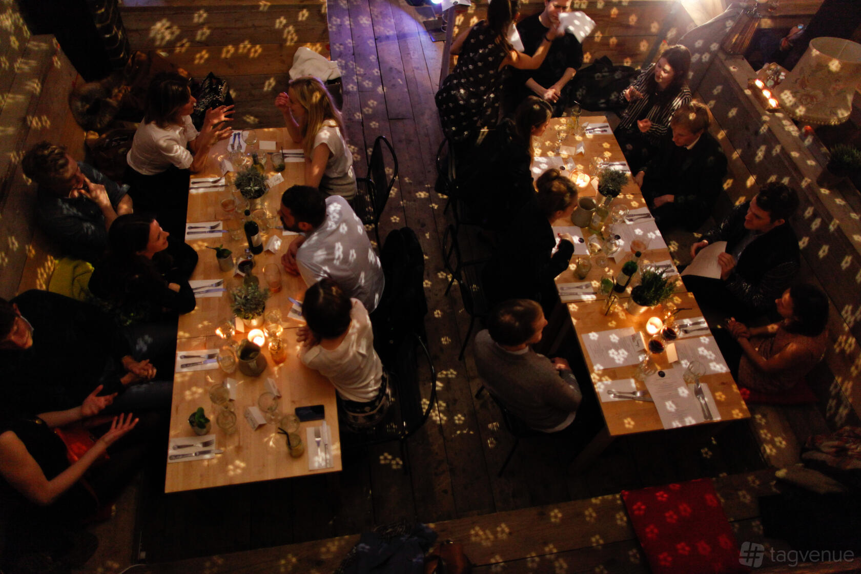 A bar with long wooden tables, candlelight, and overhead disco lights at Studio 9294.