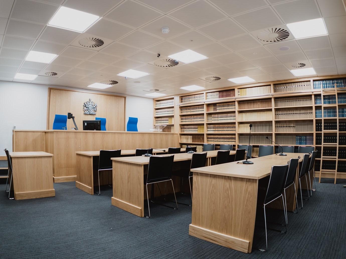 A meeting room with a mock courtroom setup, wood furnishings, and wall-to-wall bookshelves at University of Law - Leeds.