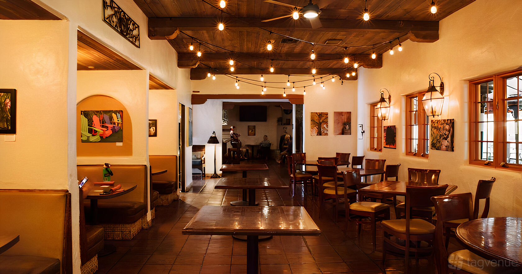 A restaurant event space with wooden ceiling beams, string lights, and a mix of booths and tables at WildWood Crossing and Cantina.