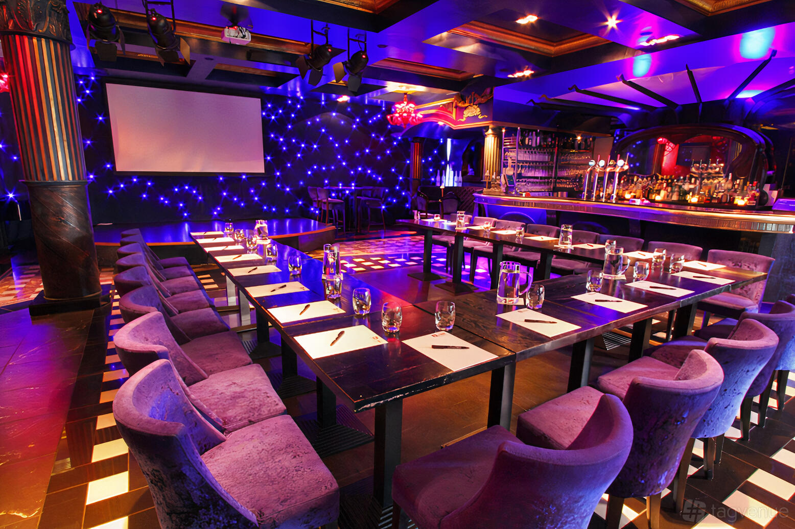 A function room with purple velvet chairs, U-shaped tables, and a backdrop of twinkling LED lights at Le Monde Hotel.