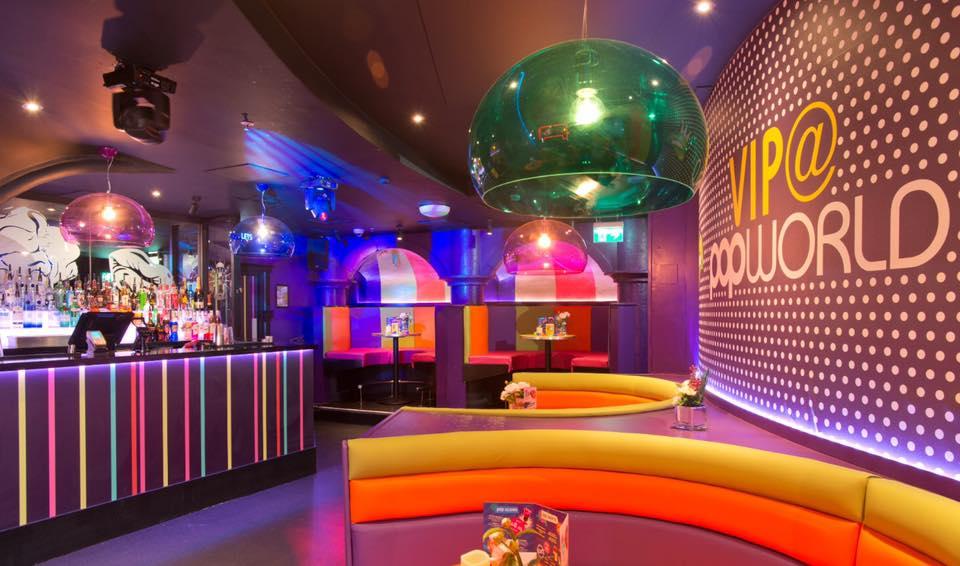 A nightclub function room with colorful curved booths, striped bar, and large hanging lights at Popworld Watling Street.