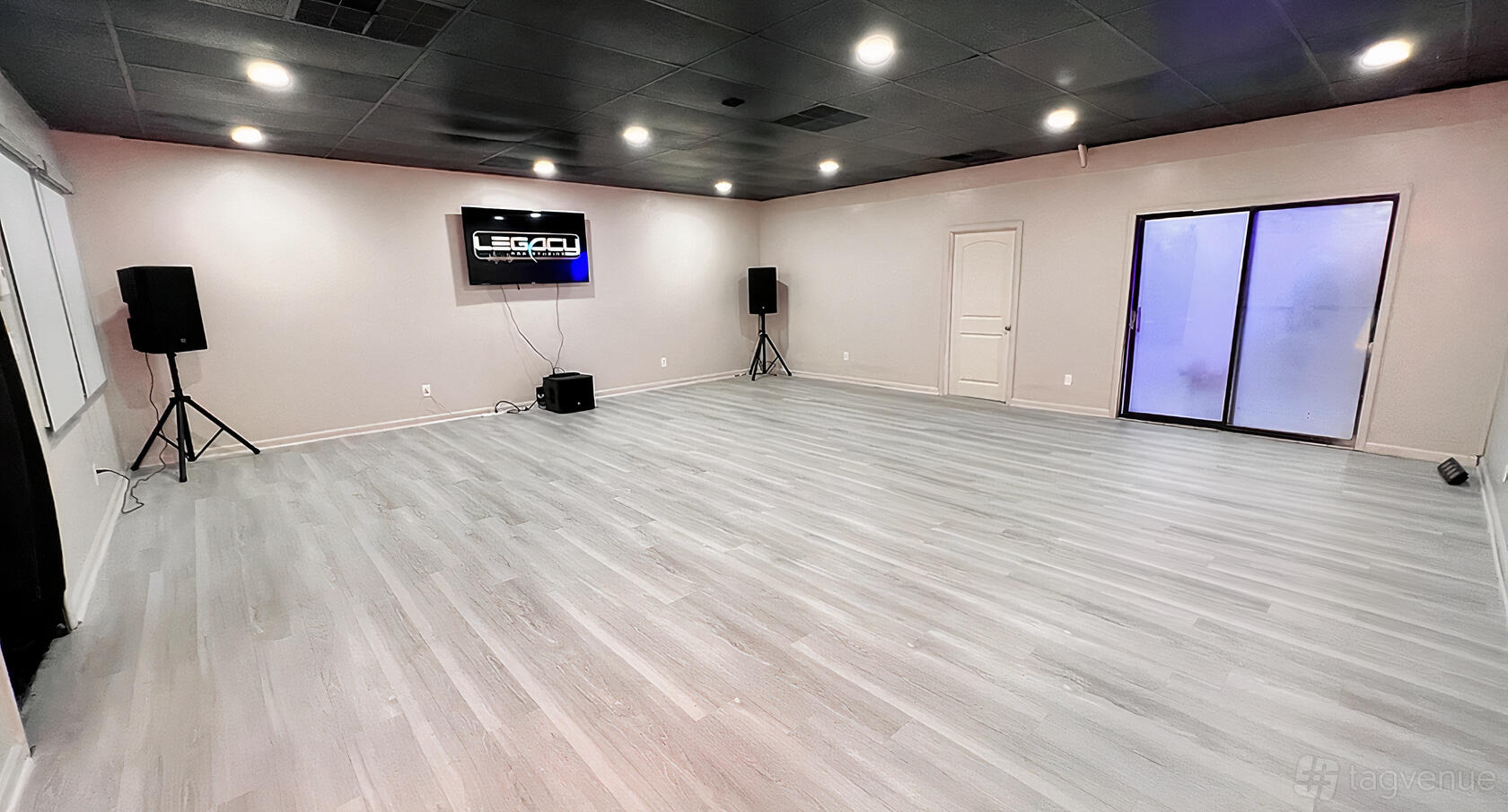 An event venue with light wood flooring, neutral walls, ceiling spotlights, and audio equipment at Legacy Pro Studios.