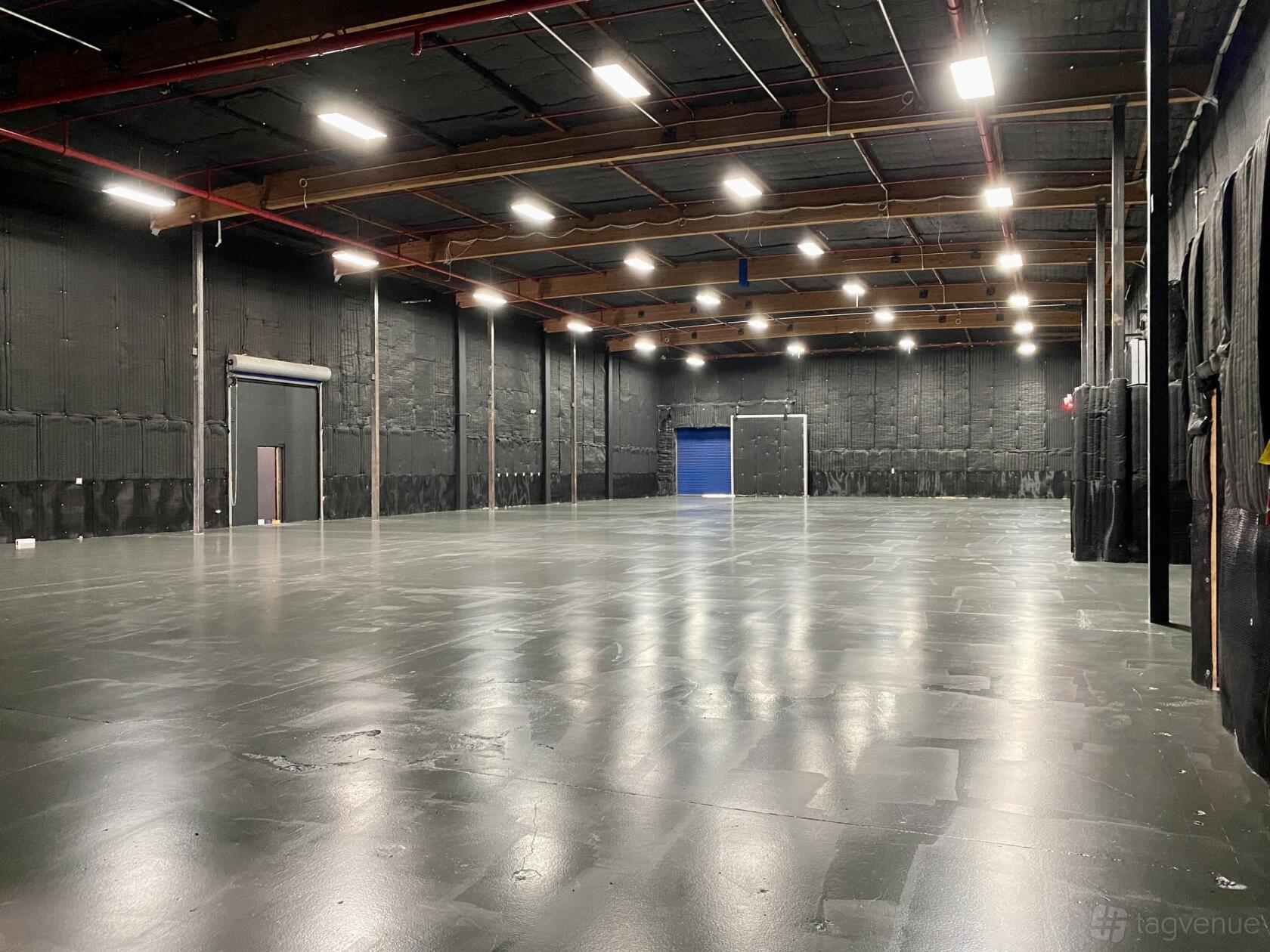 A spacious photo studio with high ceilings, overhead lighting, and black soundproofed walls at East End Studios.