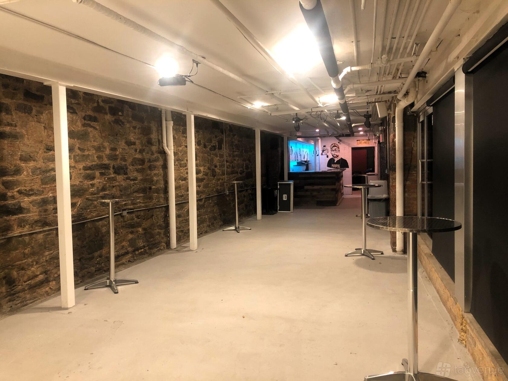 An event venue with exposed stone walls, industrial ceiling pipes, and a small check-in counter at Black Cellar Venue.