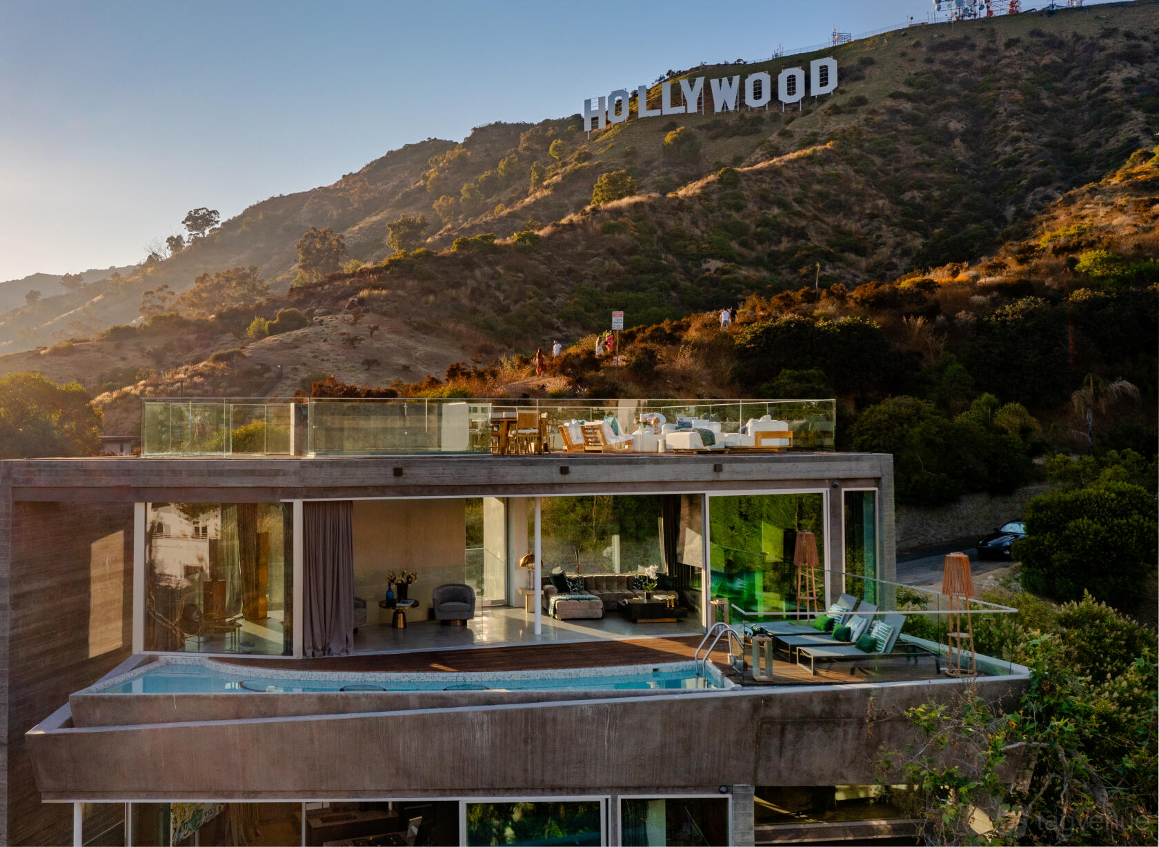 A hillside house with an outdoor pool, glass-walled terrace, and views of the Hollywood Sign at The Iconic Hollywood Sign House.