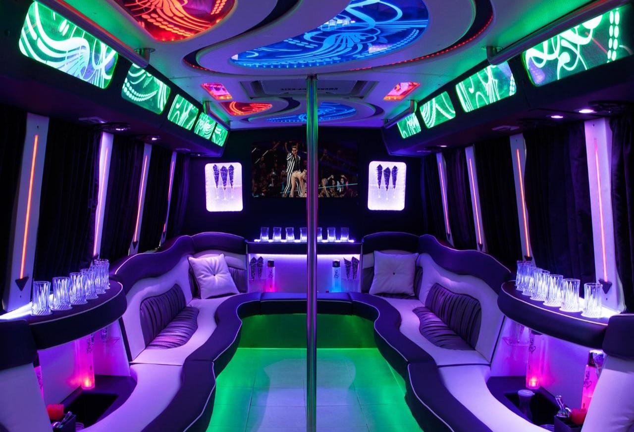 A party bus with curved leather seating, LED ceiling lights, dancing pole, and glass holders at Long Island Limo Service - 7 Star Limo.