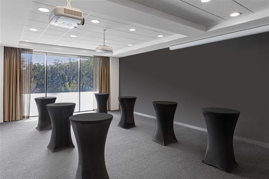 An event space with high ceilings, cocktail tables draped in black linens, and floor-to-ceiling windows at Peppers Marysville.