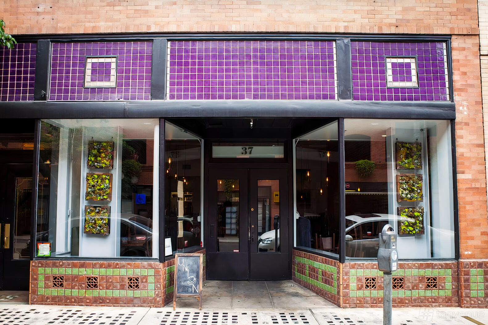 A restaurant entrance with purple tile, large windows, and green mosaic accents at Union Restaurant.