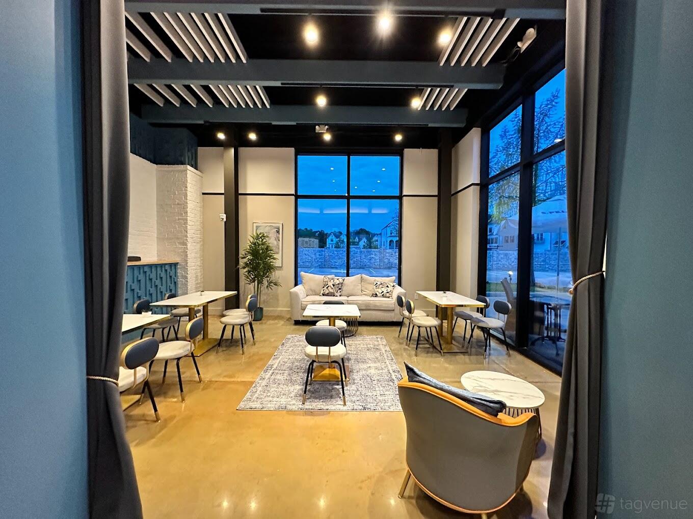 A function room in a bar with floor-to-ceiling windows, modern chairs, and a central sofa at VinSanto.