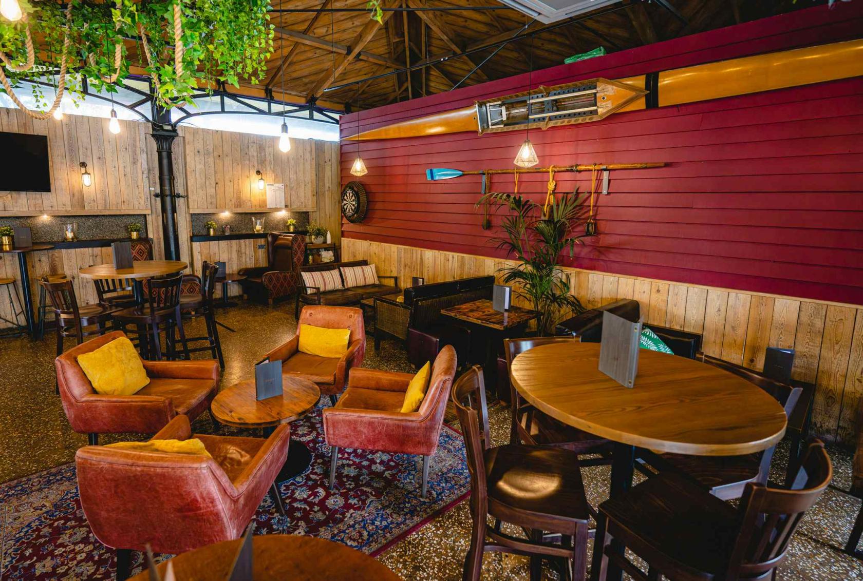 A restaurant terrace with wooden panel walls, vintage armchairs, and boating decor at Harbour House.