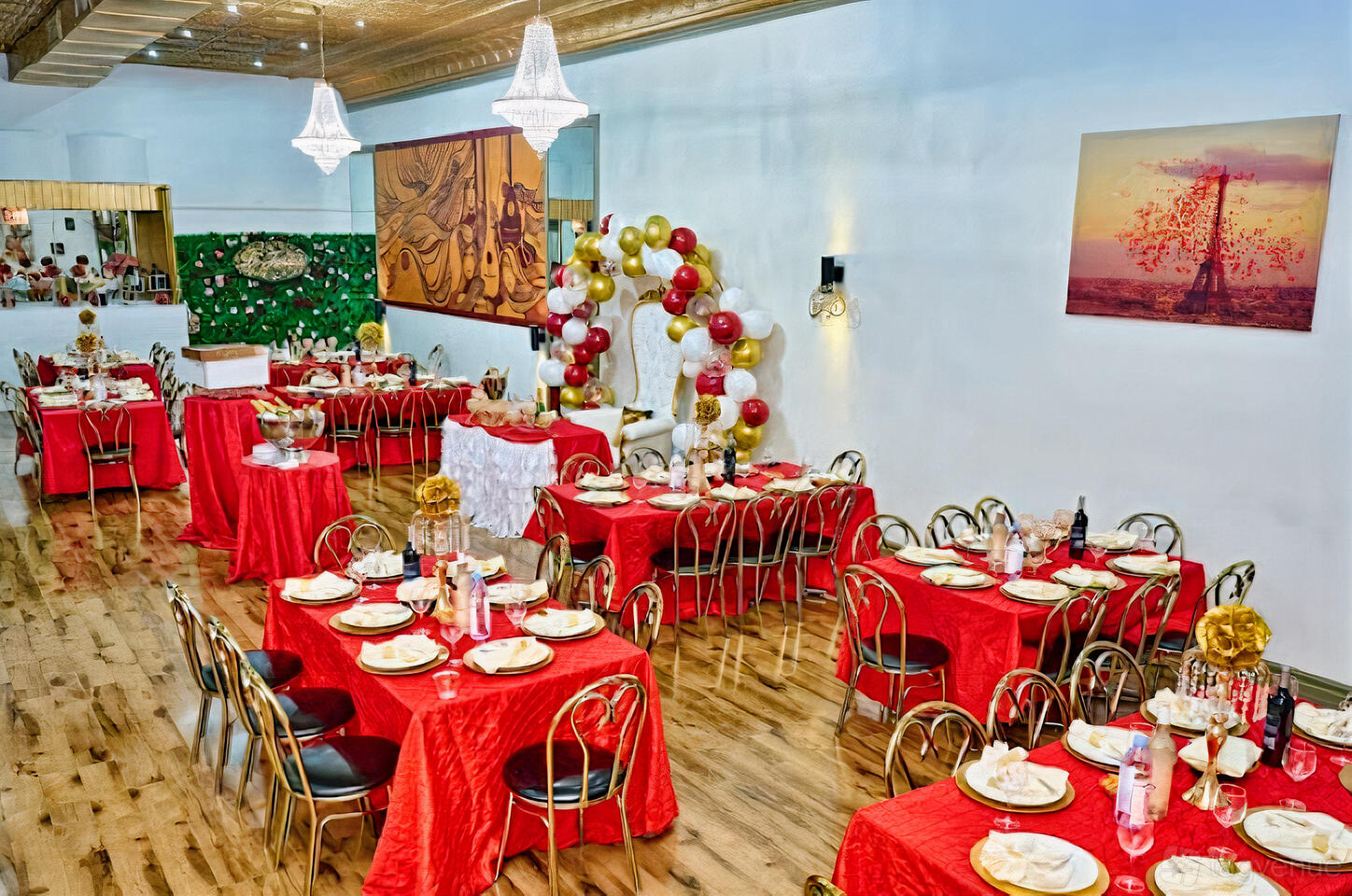 A banquet hall with red-covered tables, gold chairs, and a balloon arch at Le Jardin: Restaurant & Banquet Hall.