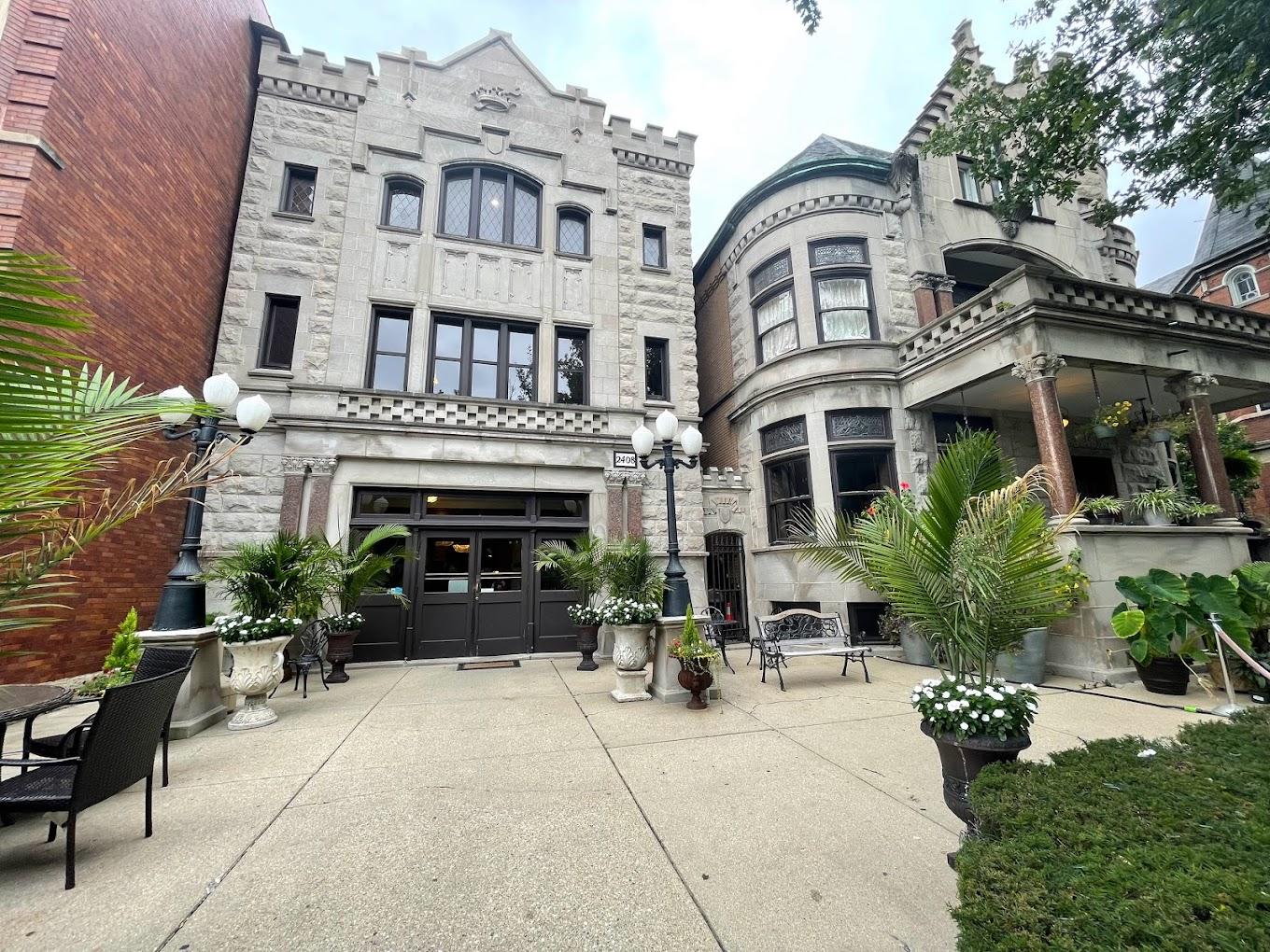 A historic stone event space with arched windows, potted palms, and vintage street lamps at Stan Mansion.