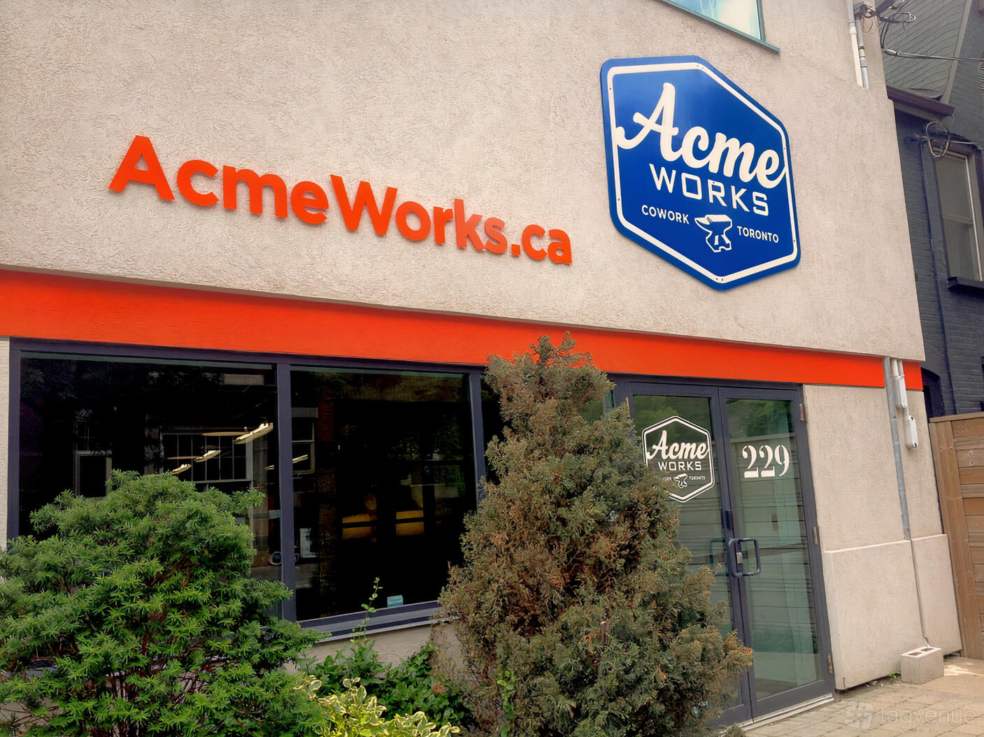 A meeting centre with large front windows, exterior signage, and greenery at ACME Works.