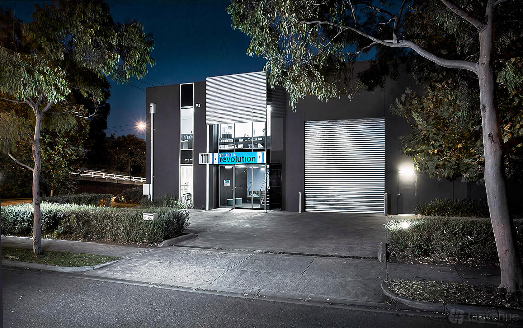 A film and photo studio with a dark facade, large metal roller door, and glass entrance at Studio Revolution.
