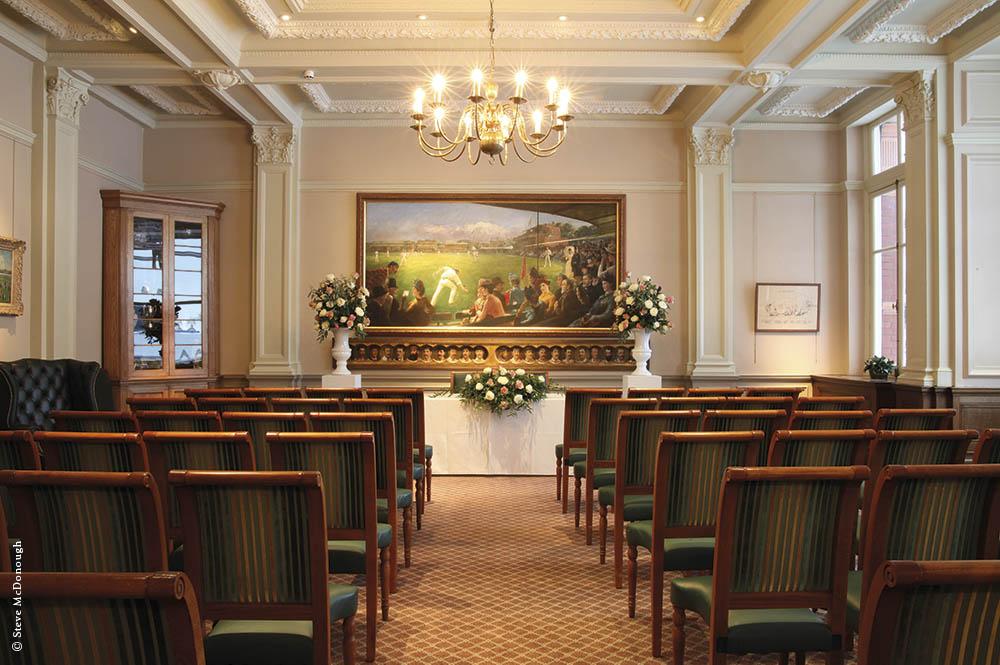 A dining room with green upholstered chairs, ornate ceiling, and a large historic painting at Lord's Cricket Ground.