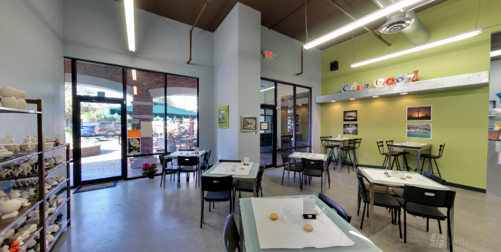A cafe with painted pottery displays, large windows, and art tables set for crafts at Cafe Monet Art and Clay Studio.