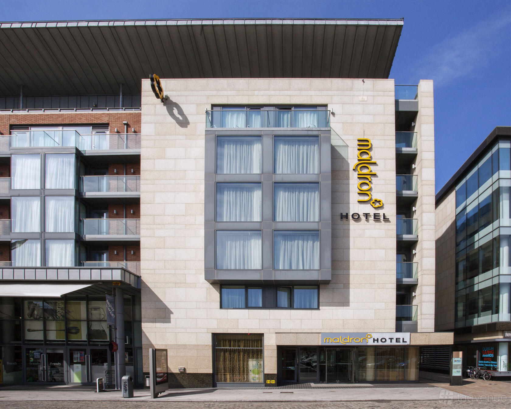 A hotel exterior with large windows, cream stone facade, and signage at Maldron Hotel Smithfield.