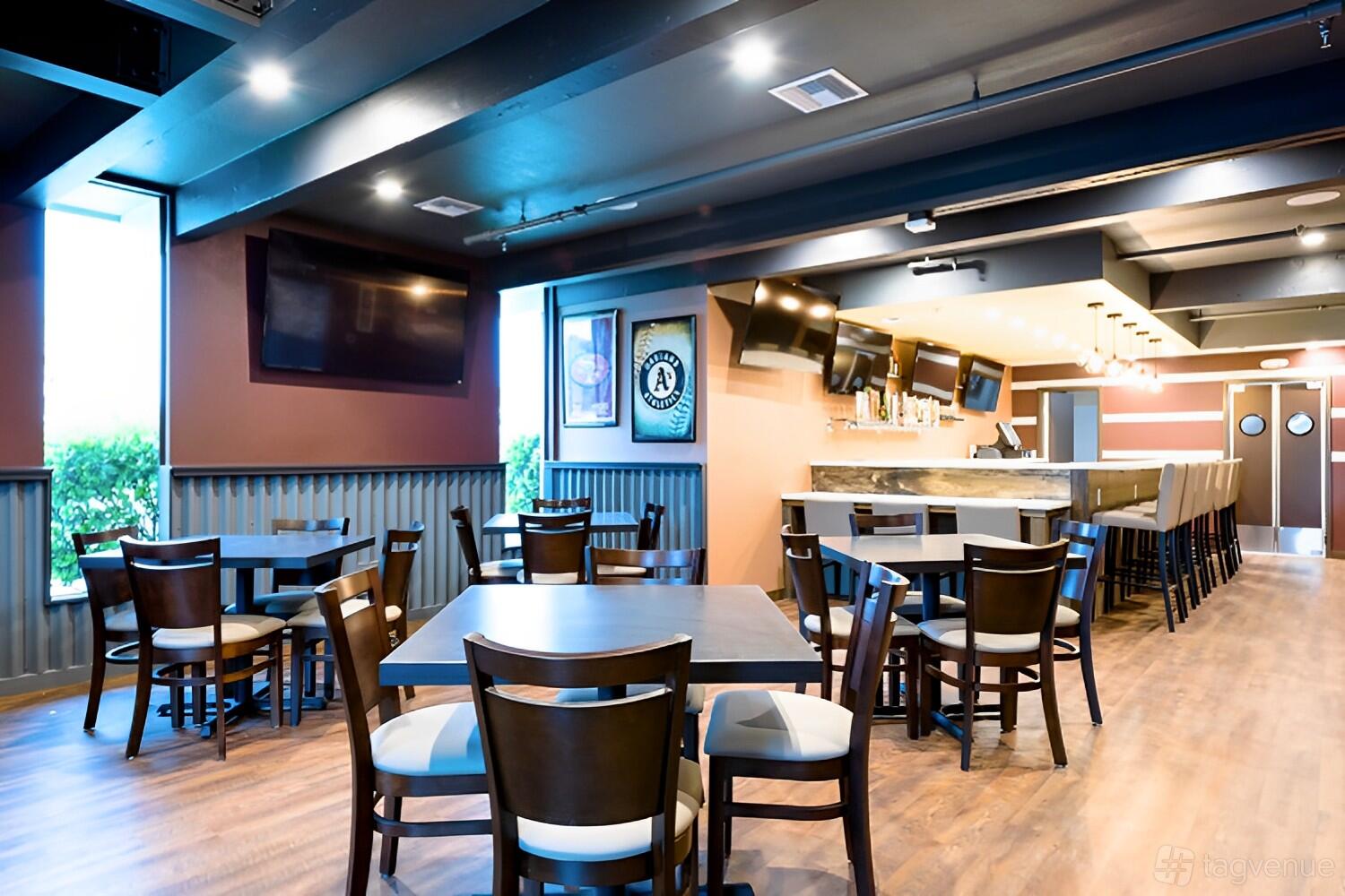 A restaurant with wood floors, multiple tables and chairs, wall-mounted TVs, and a long bar at JP's Family Restaurant.