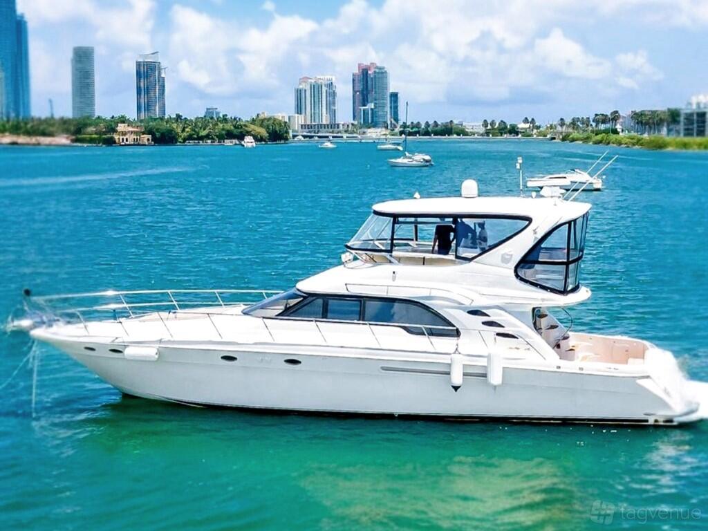 A white yacht with a multi-level flybridge and panoramic windows cruising on blue water at Ocean View Yacht Charters.
