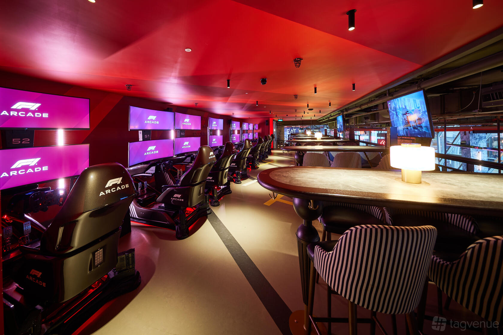 An event venue in a cocktail bar with F1 racing simulators and striped chairs at F1 Arcade, St Pauls, London.