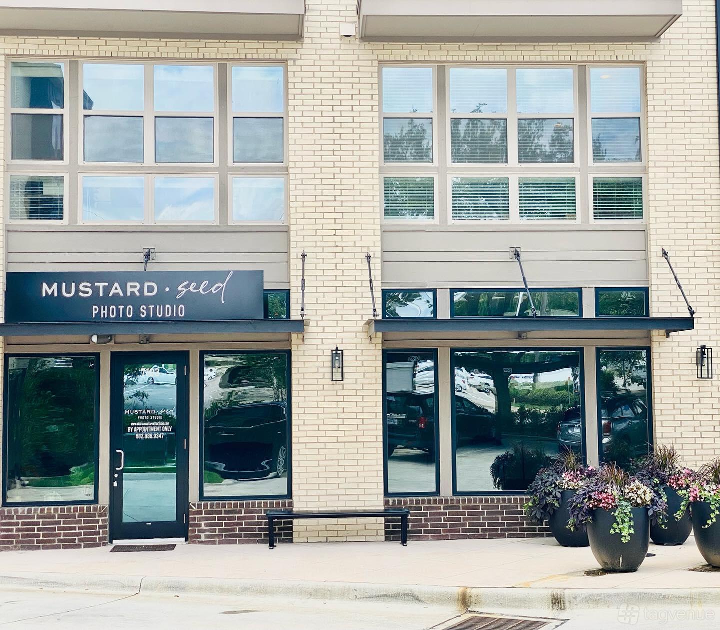 A film and photo studio with large glass windows, brick exterior, and potted plants at Mustard Seed Photo Studio.