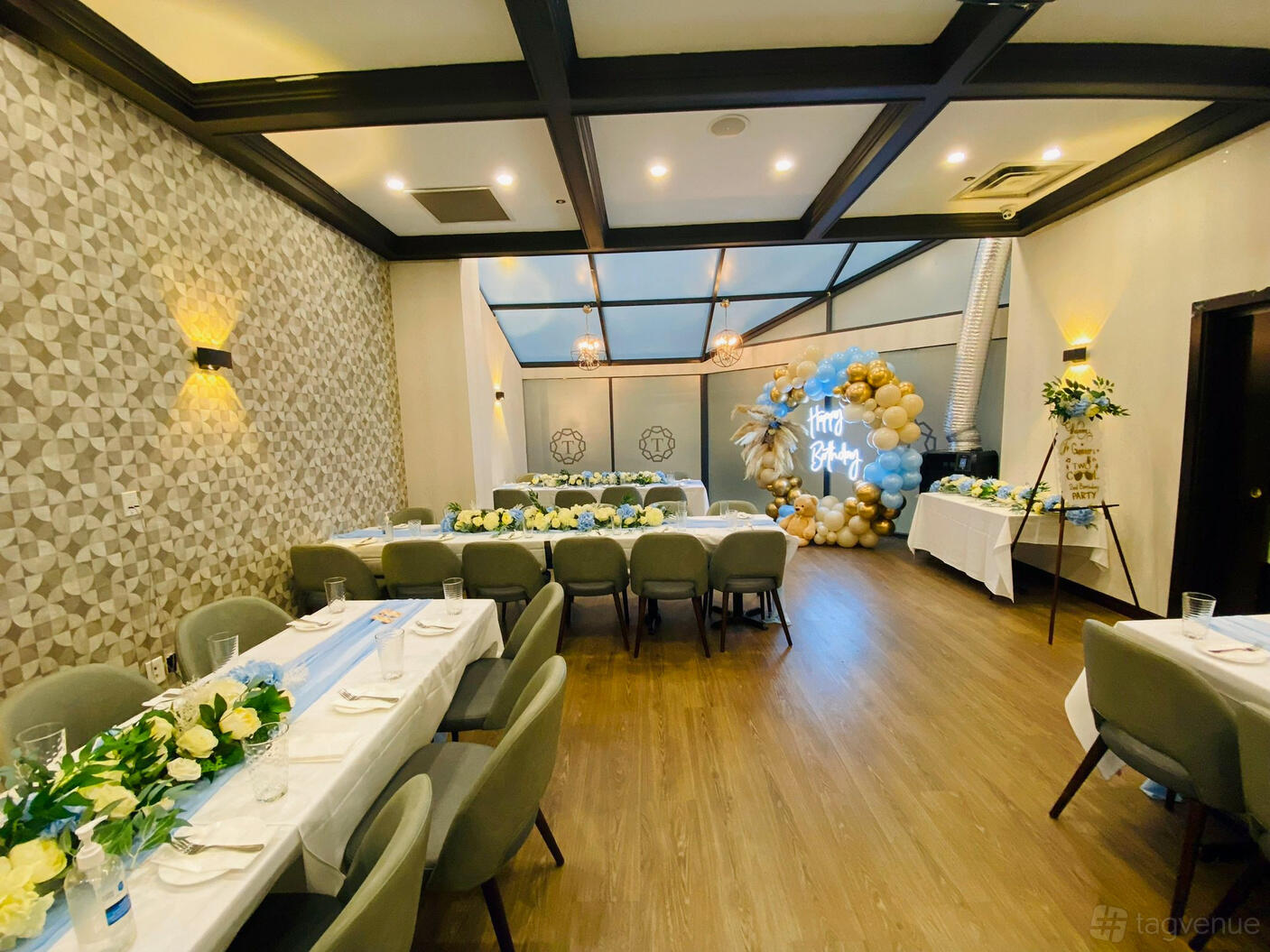 A function room in a restaurant with floral centerpieces, beige chairs, and a balloon display at Tamarind Modern Indian Bistro.