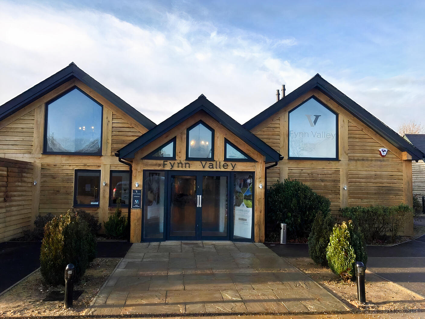 A country house with timber cladding, large triangular windows, and glass entrance doors at Fynn Valley Terrace.