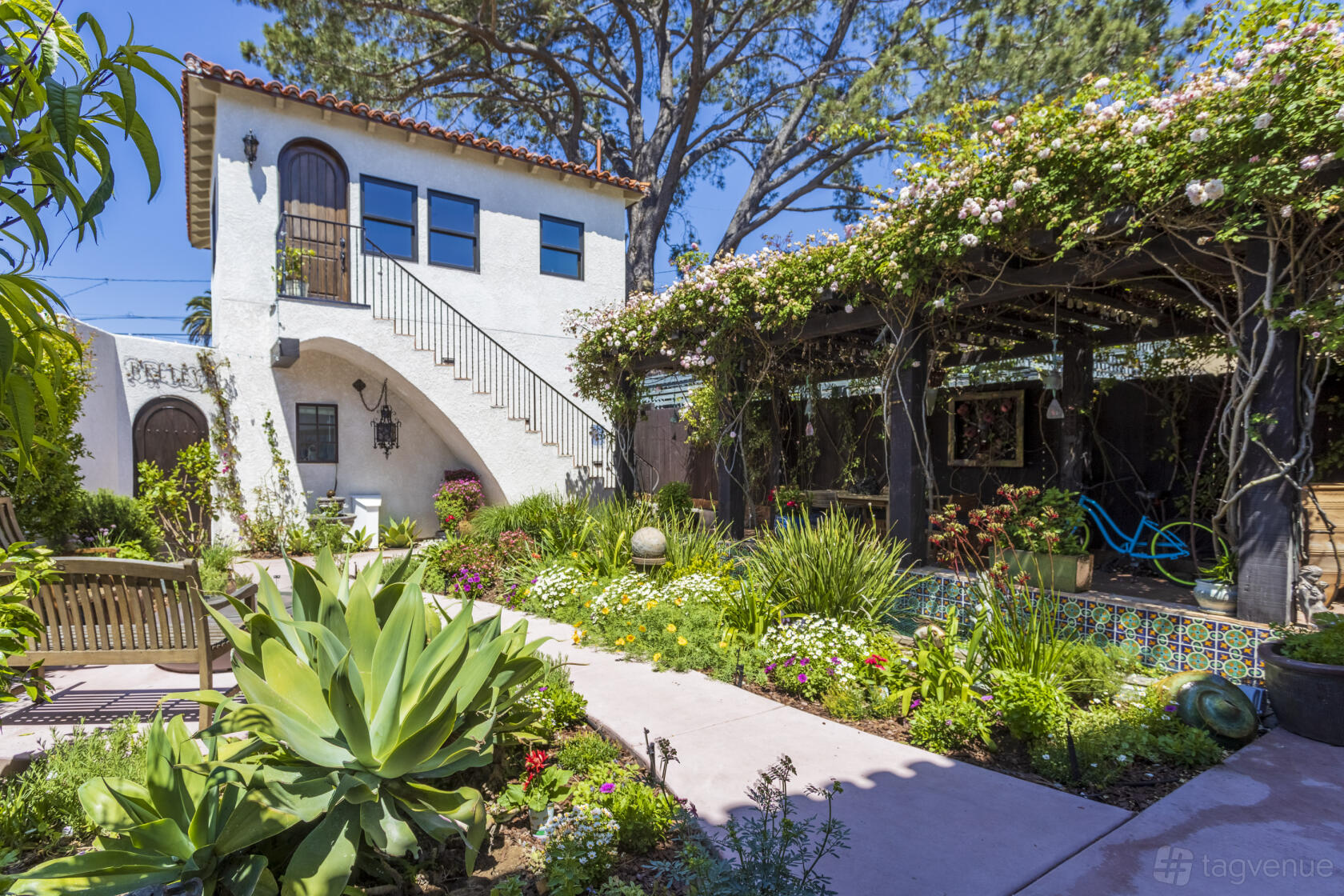 A lush garden with flowering vines on a pergola, tiled fountain, and Mediterranean-style house at Villa Francesca.