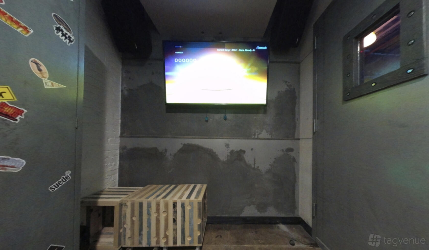 An event venue room with a wall-mounted TV, gray painted walls, and a wooden crate table at RPM Underground.