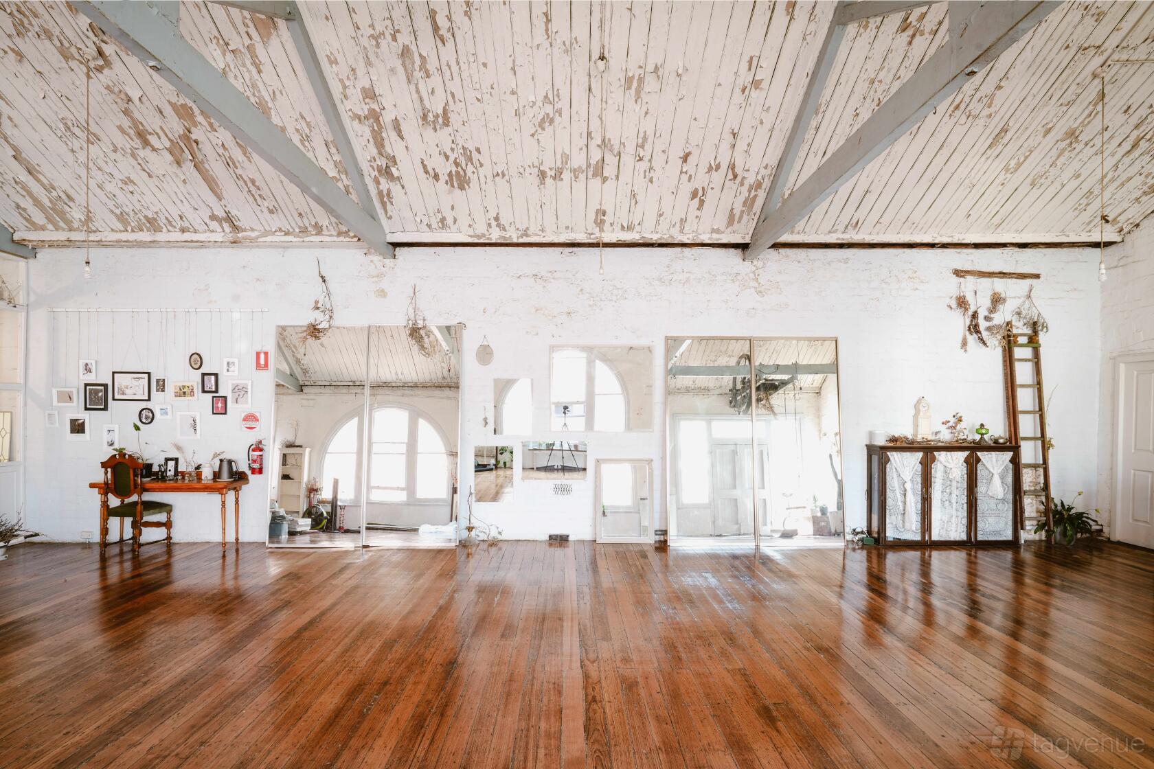 A loft with distressed white wooden ceilings, exposed beams, and polished hardwood floors at CBD.