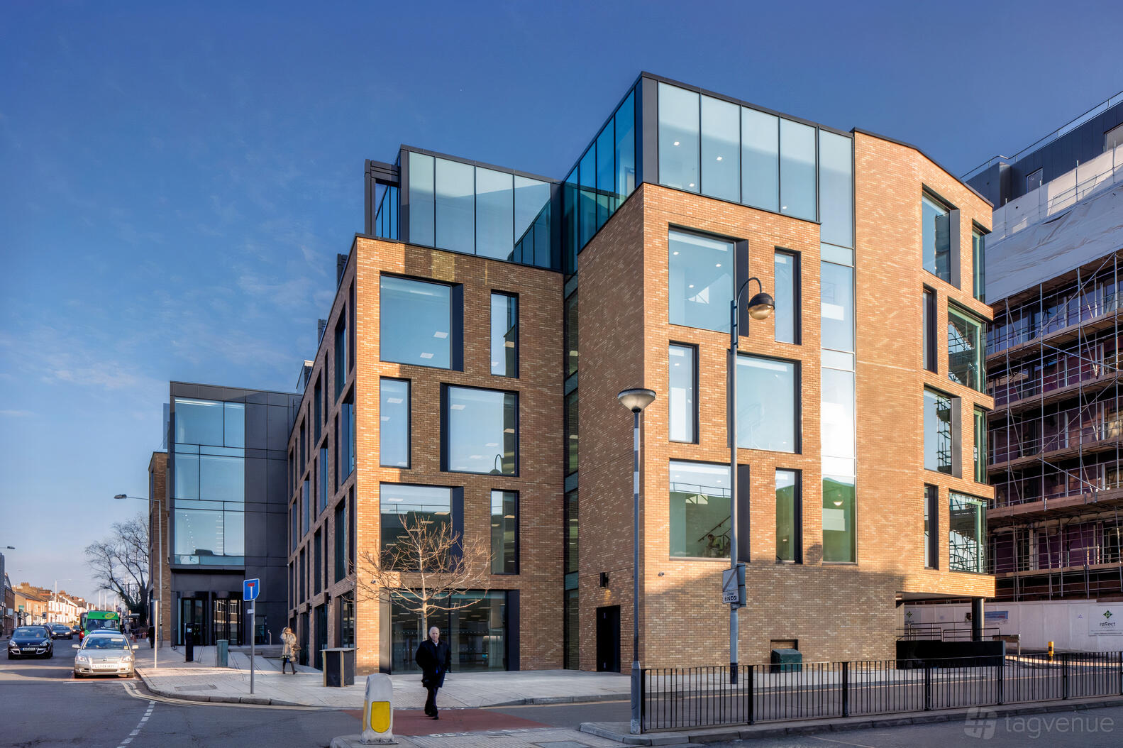 A coworking space with large floor-to-ceiling windows and a brick exterior at Orega Uxbridge.