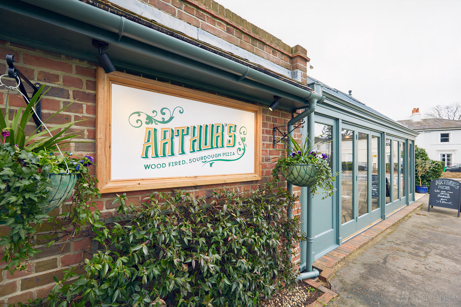 A restaurant with brick walls, large windows, and hanging flower baskets at Arthur's.