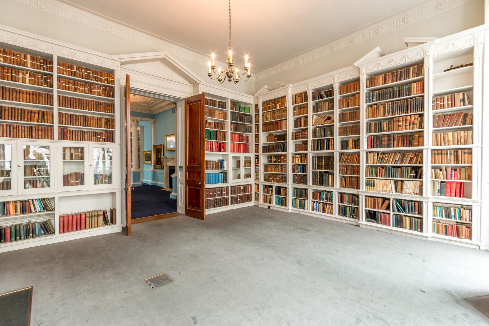 A function room with floor-to-ceiling bookshelves filled with books and a chandelier at The Royal Institution.